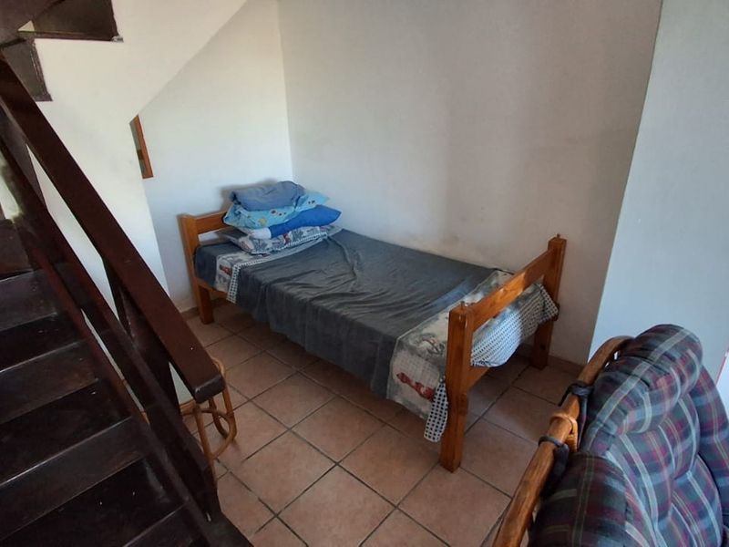 A bedroom space situated beneath a staircase, featuring tiled flooring and neutral wall finishes.