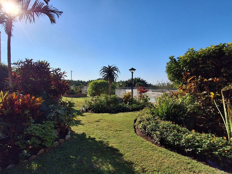 A well-maintained landscaped garden featuring a manicured lawn, established shrubs, and perimeter fencing, providing a pleasant outdoor space.