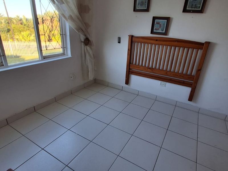 A bedroom featuring tiled flooring, a window with security bars, and a built-in cupboard, offering a functional space ready for personalization.