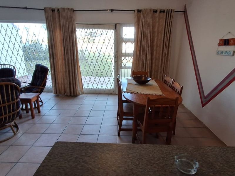 Open plan living and dining area featuring tiled flooring and direct access to the outdoor space through a sliding glass door with security gate.