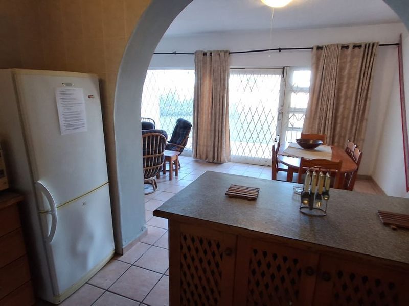 Open plan kitchen and dining area featuring tiled floors, wooden cabinetry, and a distinctive architectural archway leading to the living space.
