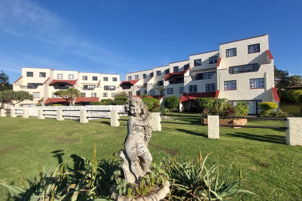 A view of the rear apartment complex facade featuring multi-story units with balconies, set against a well-maintained communal lawn and garden area.
