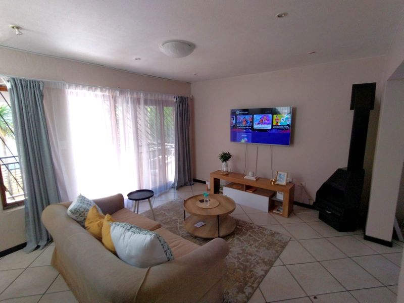 A comfortable living room featuring tiled flooring, a freestanding fireplace, and large sliding glass doors that provide ample natural light.