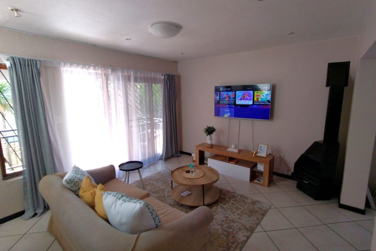 A comfortable living room featuring tiled flooring, a freestanding fireplace, and large sliding glass doors that provide ample natural light.