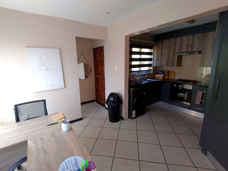 Open plan kitchen area featuring modern cabinetry, built-in oven and hob, tiled flooring, and direct access to the home entrance.