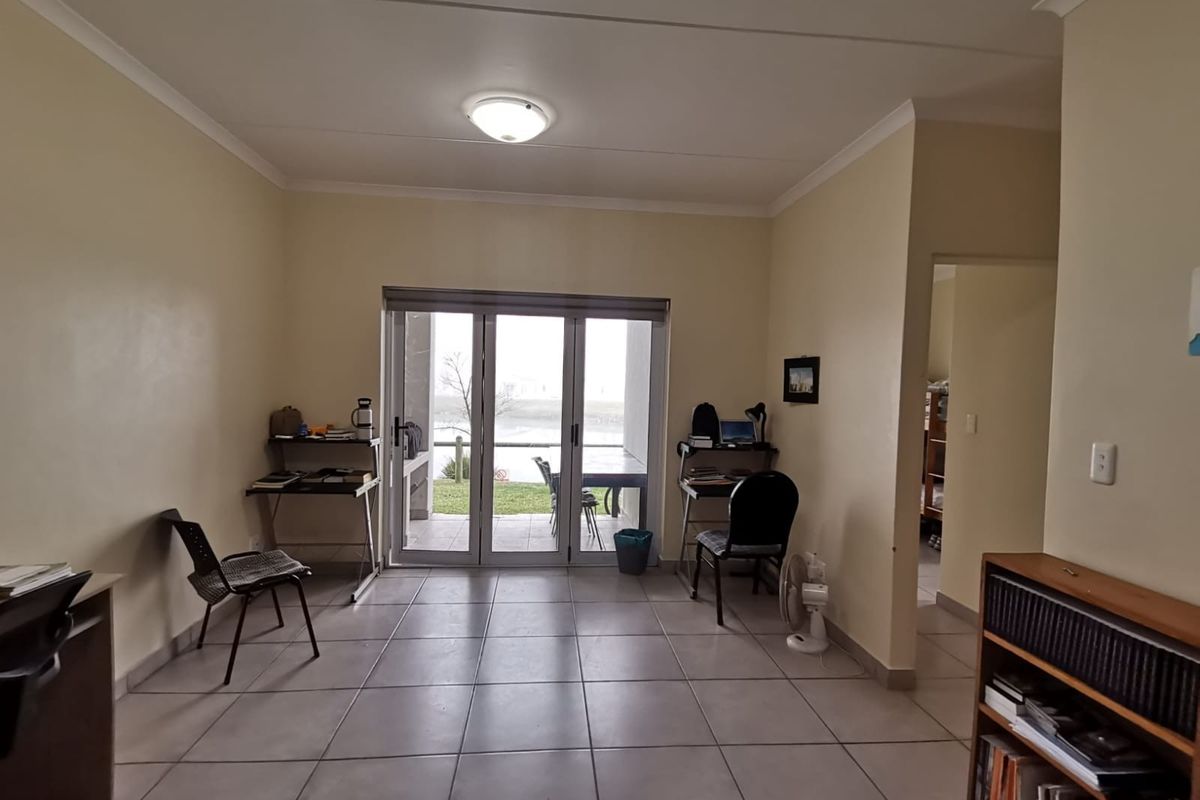 Spacious living area featuring neutral tiled flooring and large sliding glass doors that provide natural light and access to the outdoor patio area.