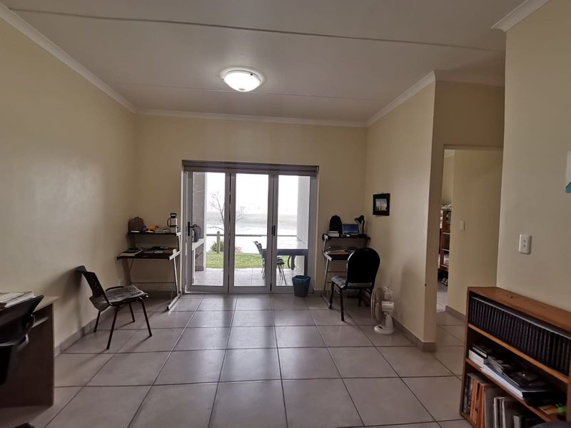 Spacious living area featuring neutral tiled flooring and large sliding glass doors that provide natural light and access to the outdoor patio area.