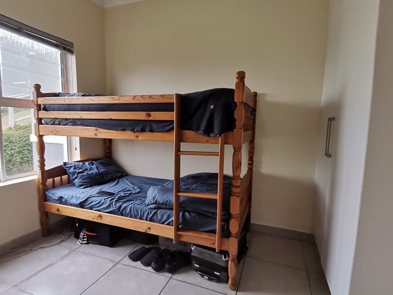 A functional bedroom featuring tiled flooring, a built-in wardrobe, and a window providing natural light.