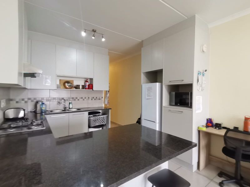 Modern kitchen featuring granite countertops, gas hob, extractor fan, and ample built-in cabinetry with a functional layout and integrated appliance housing.