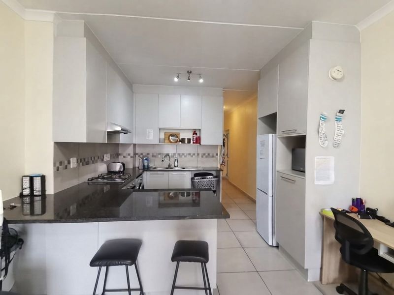 Modern kitchen featuring granite countertops, built-in cabinetry, gas hob, extractor fan, and tiled flooring, offering a functional and clean cooking space.