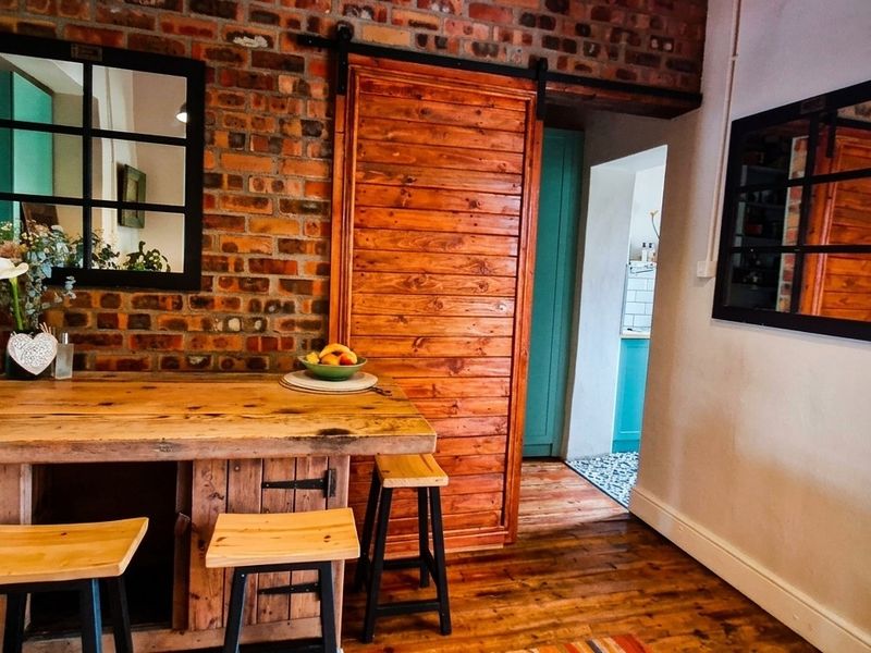 A charming kitchen area featuring exposed brick walls, a rustic sliding barn door, and warm hardwood flooring, creating a cozy and character-filled space.