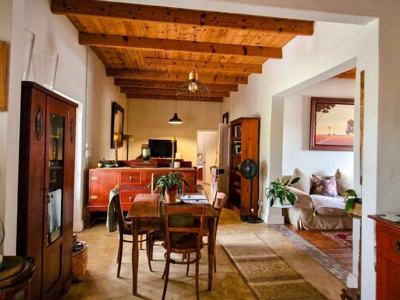 Open plan living and dining area featuring exposed timber ceiling beams and polished concrete flooring, creating a warm and rustic atmosphere.