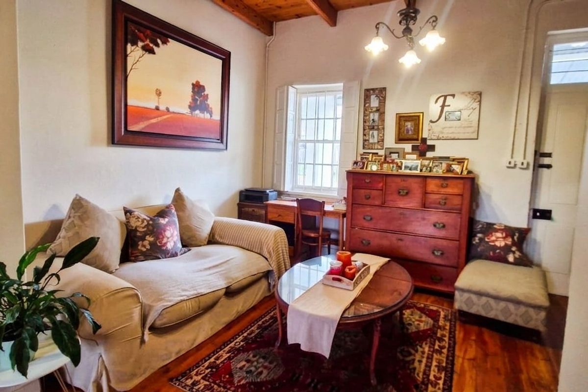 A cozy living room featuring exposed timber ceiling beams, warm timber flooring, and a classic sash window, creating a comfortable and inviting atmosphere.