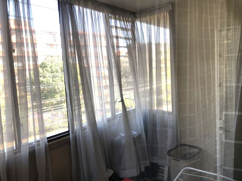 An enclosed balcony area featuring large windows with natural light and tiled wall finishes, offering a versatile space for potential use.