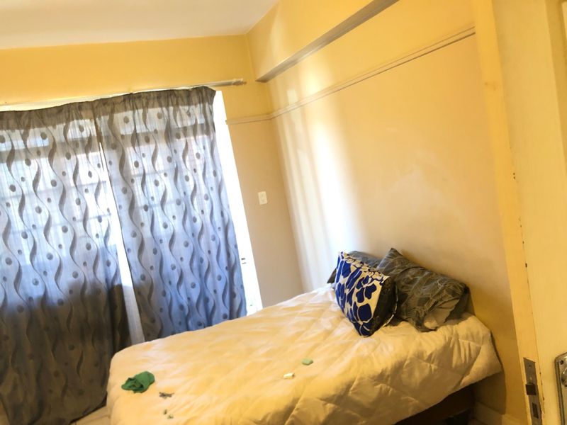 A bedroom featuring a neutral wall finish, a picture rail, and a window dressed with curtains.