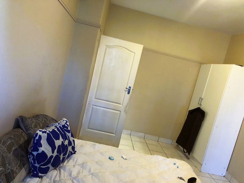 A bedroom featuring tiled flooring and a standard panel door, offering a functional space ready for personalization.