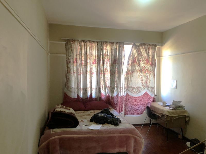 A bedroom featuring a large window with a curtain rail and traditional picture rail molding, requiring cosmetic updates to improve the overall finish.