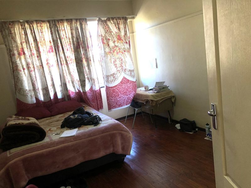 A bedroom featuring original hardwood flooring and a picture rail, requiring cosmetic updates to improve its overall condition and appeal.