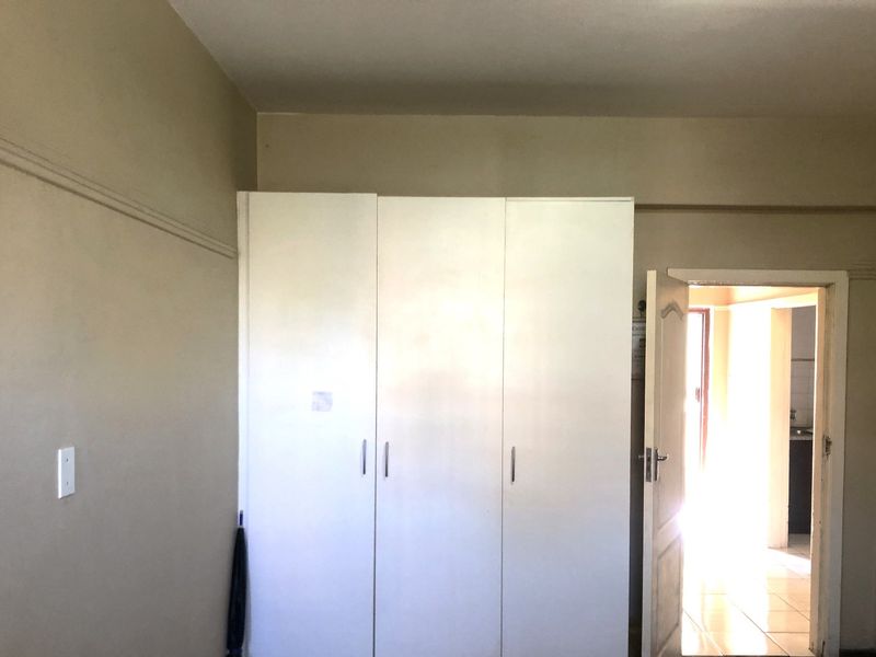 A bedroom featuring a built-in white wardrobe and classic picture rail detailing, offering a clean and functional space.