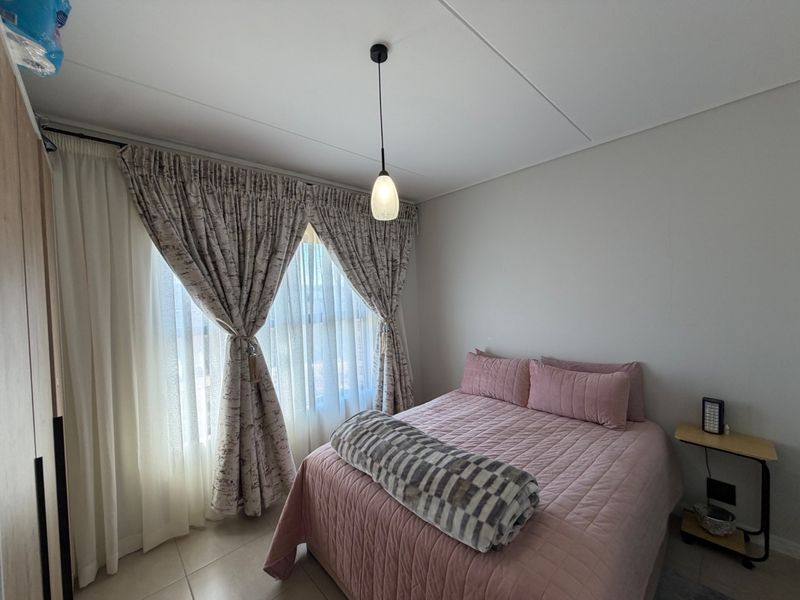A well-maintained bedroom featuring tiled flooring, a built-in wardrobe, and a modern pendant light fixture.