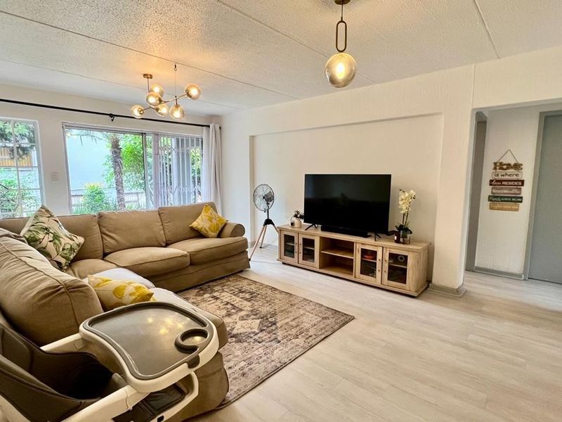 A bright and spacious living room featuring laminate flooring, textured ceilings, and large sliding glass doors that provide ample natural light.