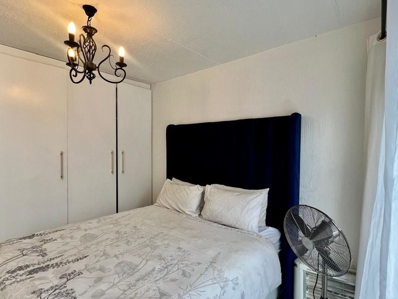 A functional bedroom featuring built-in cupboards and a central ceiling light fixture, providing essential storage and lighting.