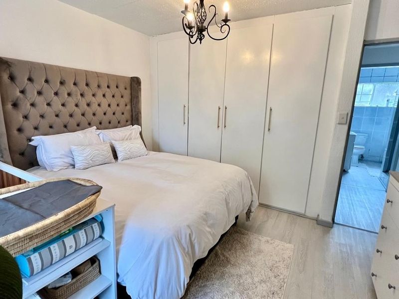 A well-maintained bedroom featuring built-in cupboards, laminate flooring, and direct access to an en-suite bathroom.