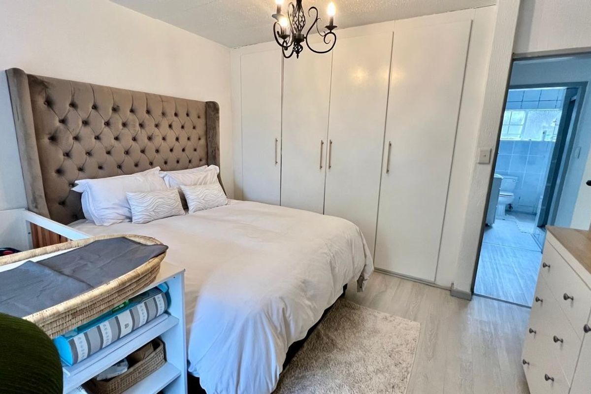 A well-maintained bedroom featuring built-in cupboards, laminate flooring, and direct access to an en-suite bathroom.
