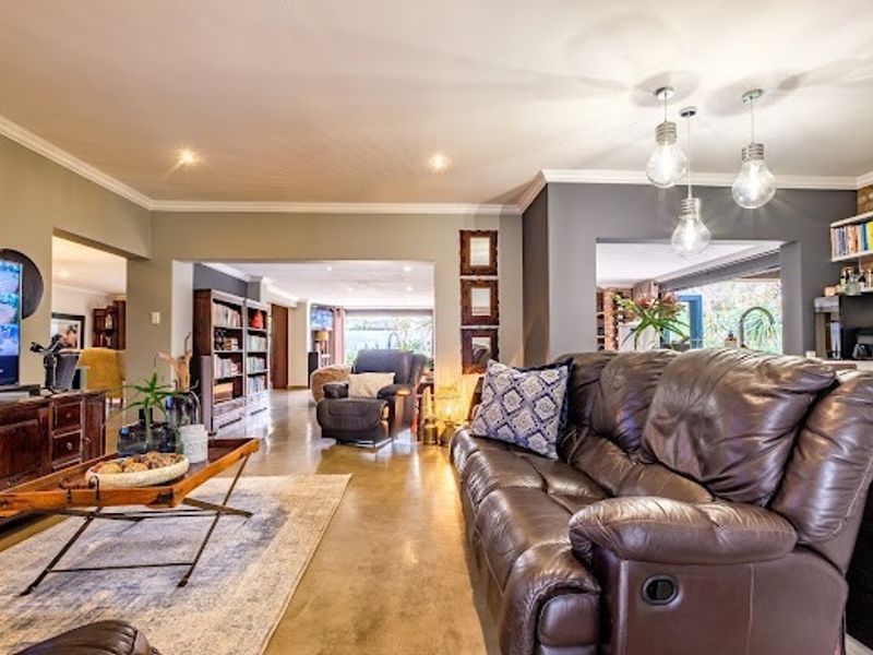 Spacious open-plan living area featuring polished concrete floors, modern pendant lighting, and neutral wall tones, creating a bright and connected living space.