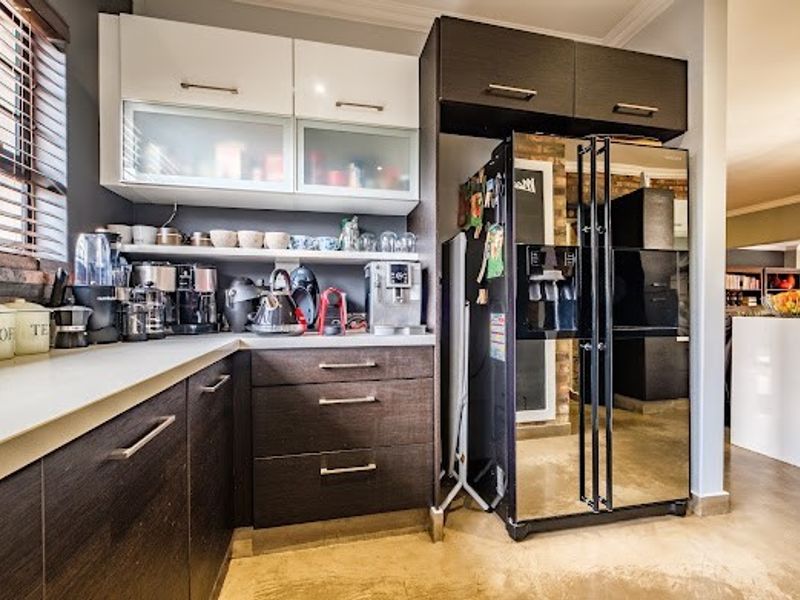Modern kitchen featuring dark wood-grain cabinetry, contrasting white upper cabinets, and ample counter space for food preparation.