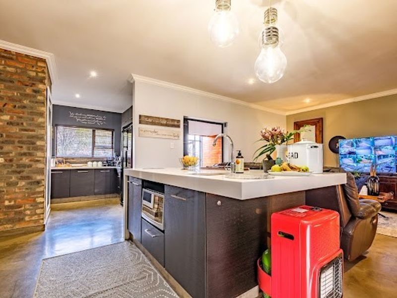 Modern open-plan living area featuring a central kitchen island, polished concrete floors, and an exposed brick feature wall, creating a warm, contemporary atmosphere.