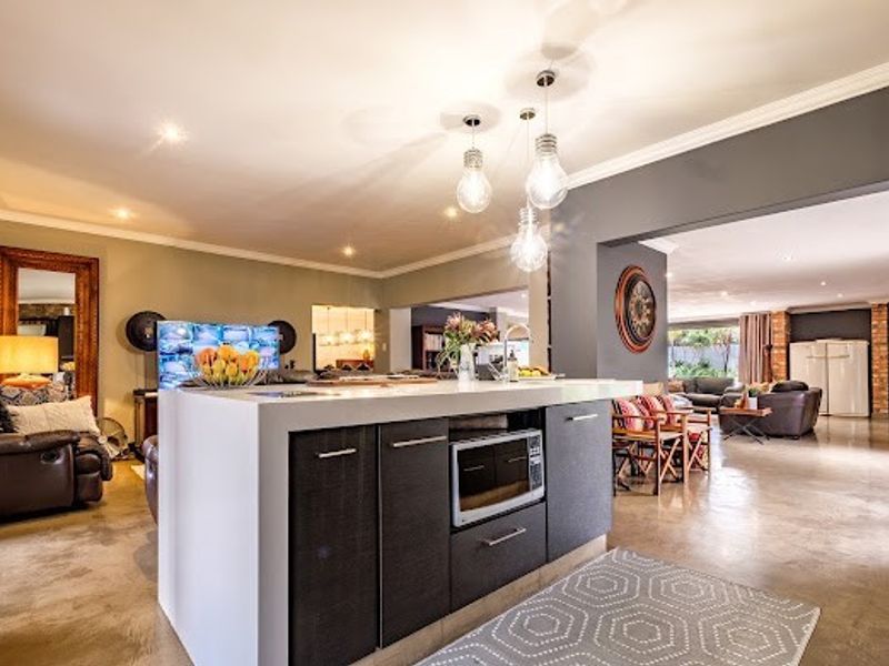 Spacious open-plan living area featuring a modern kitchen island with built-in microwave, pendant lighting, and polished concrete flooring throughout.