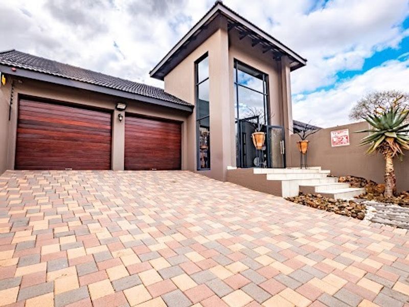 Modern front elevation featuring a double garage with timber-look doors, a paved driveway, and a striking entrance with full-height glass windows.