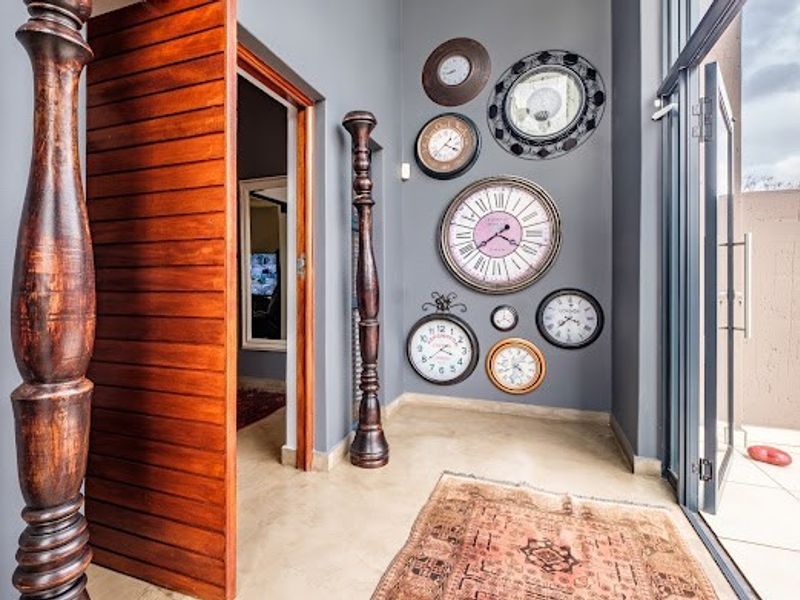 An inviting entrance hall featuring a large wooden pivot door, tiled flooring, and a glass sliding door leading to an outdoor area.