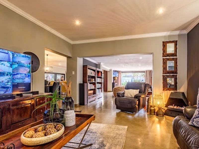 Spacious living area featuring polished concrete floors, recessed downlighting, crown molding, and a built-in fireplace, creating a warm and inviting atmosphere.