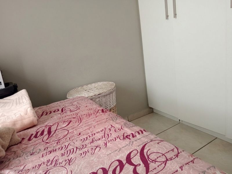A bedroom featuring neutral wall tones, tiled flooring, and a built-in wardrobe with white doors.