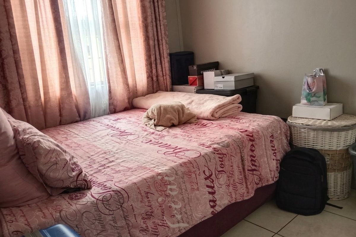 A bedroom featuring tiled flooring and a window with curtains, providing a functional space for rest.