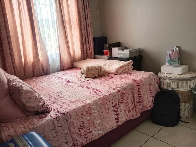 A bedroom featuring tiled flooring and a window with curtains, providing a functional space for rest.
