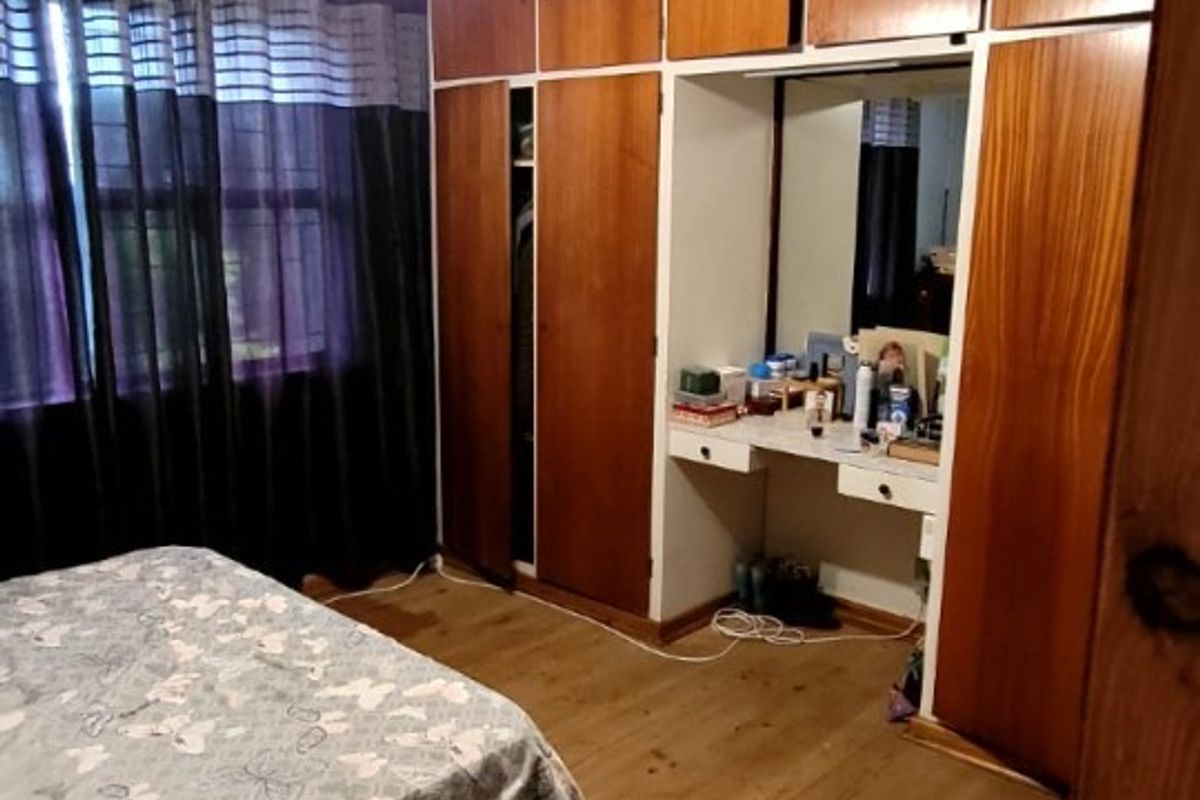 Bedroom featuring built-in wooden cupboards with an integrated vanity area, ceiling fan, and laminate flooring.