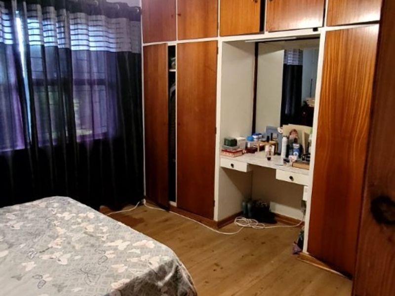 Bedroom featuring built-in wooden cupboards with an integrated vanity area, ceiling fan, and laminate flooring.