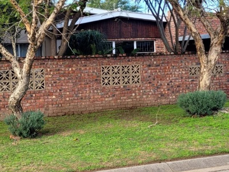 Front view of the property featuring a brick boundary wall with decorative breeze blocks and timber cladding on the house facade.