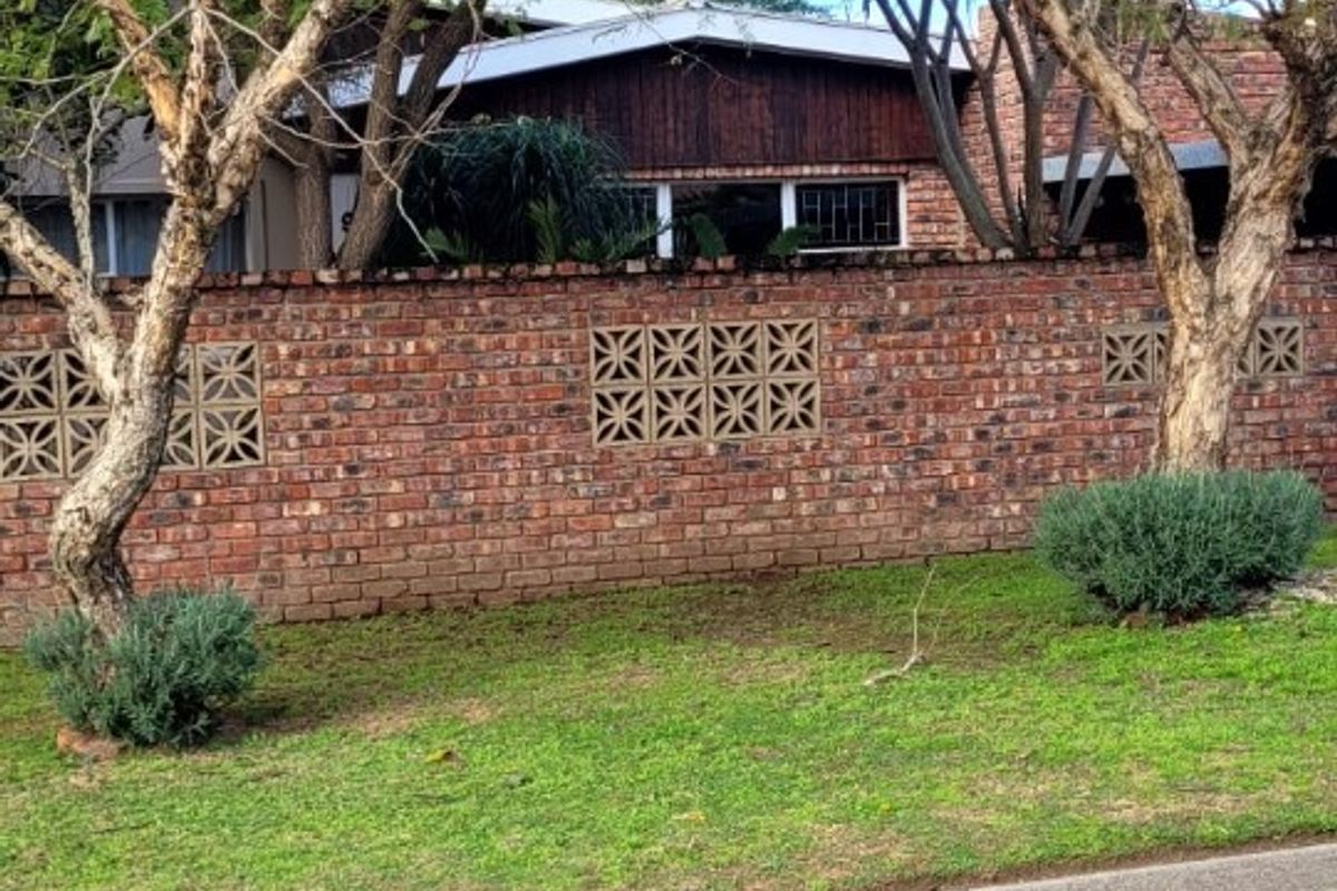 Front view of the property featuring a brick boundary wall with decorative breeze blocks and timber cladding on the house facade.