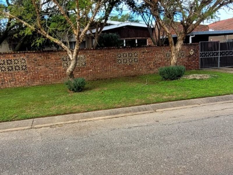 Street view of the property frontage featuring a brick boundary wall with decorative breeze blocks and a metal driveway gate.