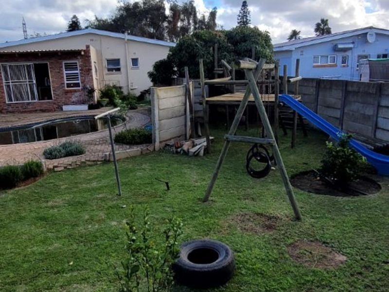 A rear garden area featuring a swimming pool, paved patio space, and perimeter boundary walling.