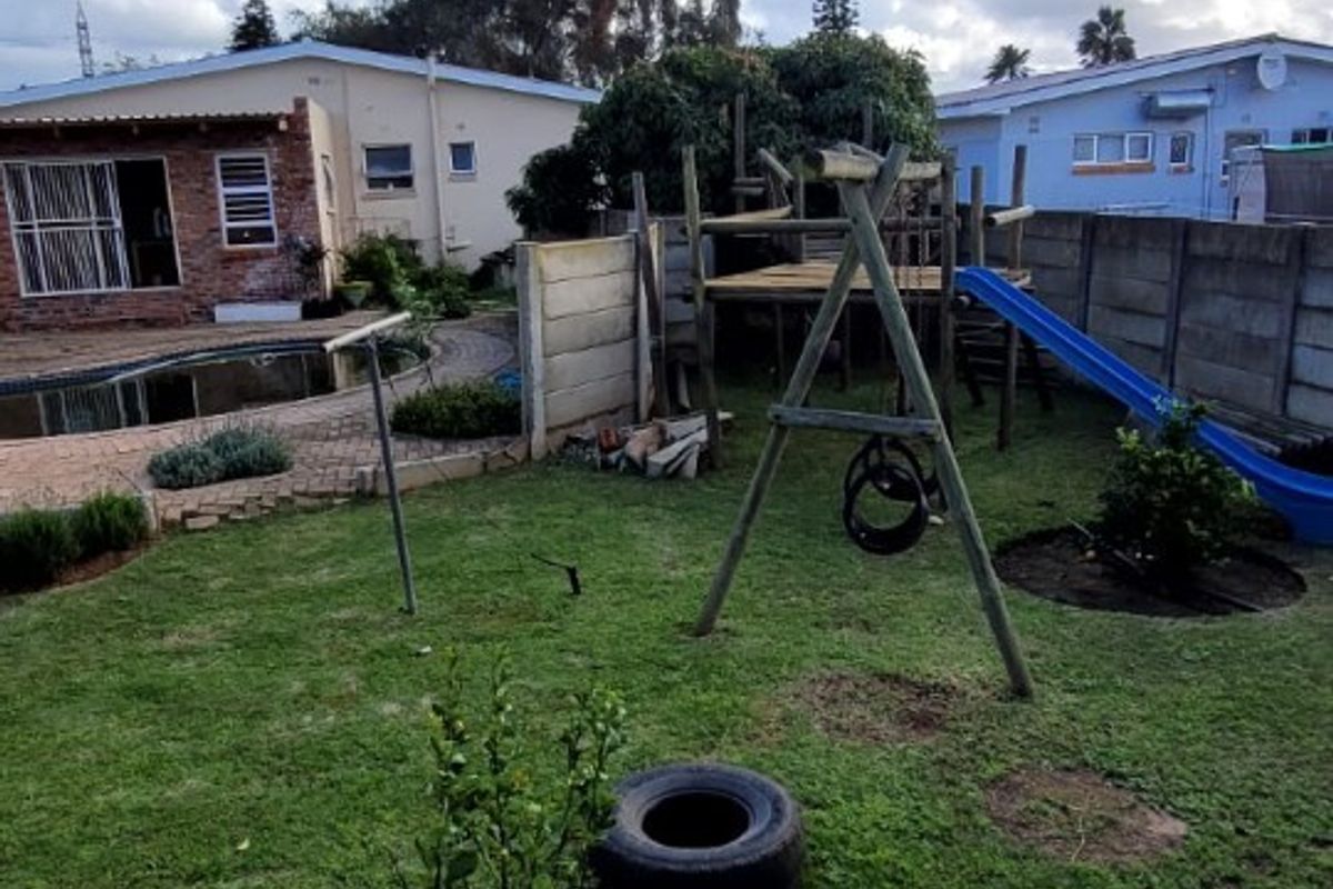 A rear garden area featuring a swimming pool, paved patio space, and perimeter boundary walling.