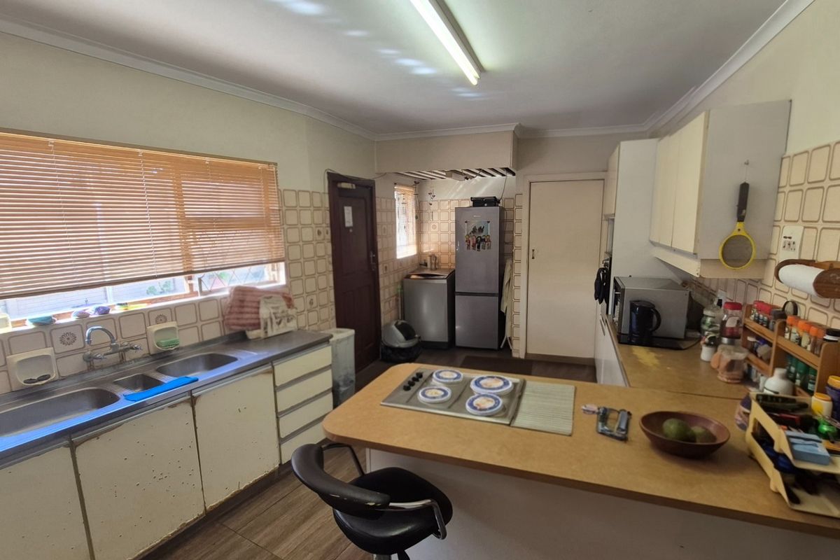 A functional kitchen featuring double basin sink, built-in cabinetry, laminate countertops, and a built-in hob with tiled splashback.