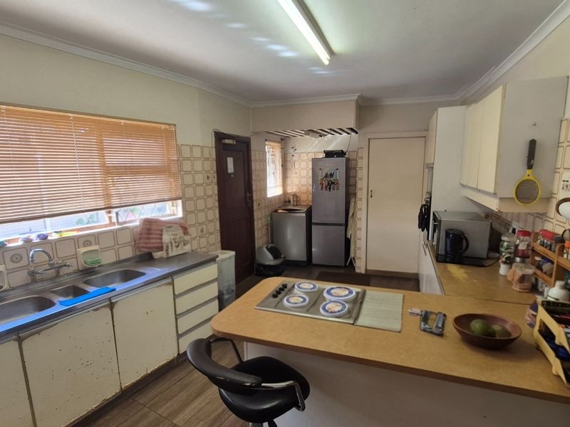 A functional kitchen featuring double basin sink, built-in cabinetry, laminate countertops, and a built-in hob with tiled splashback.
