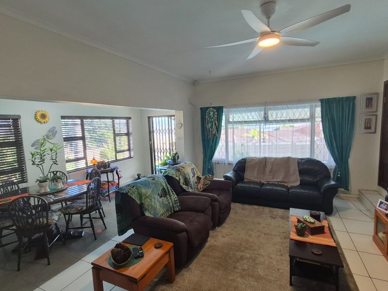 Spacious open-plan living and dining area featuring tiled flooring, a ceiling fan, and large windows with blinds, providing a functional and well-lit living space.