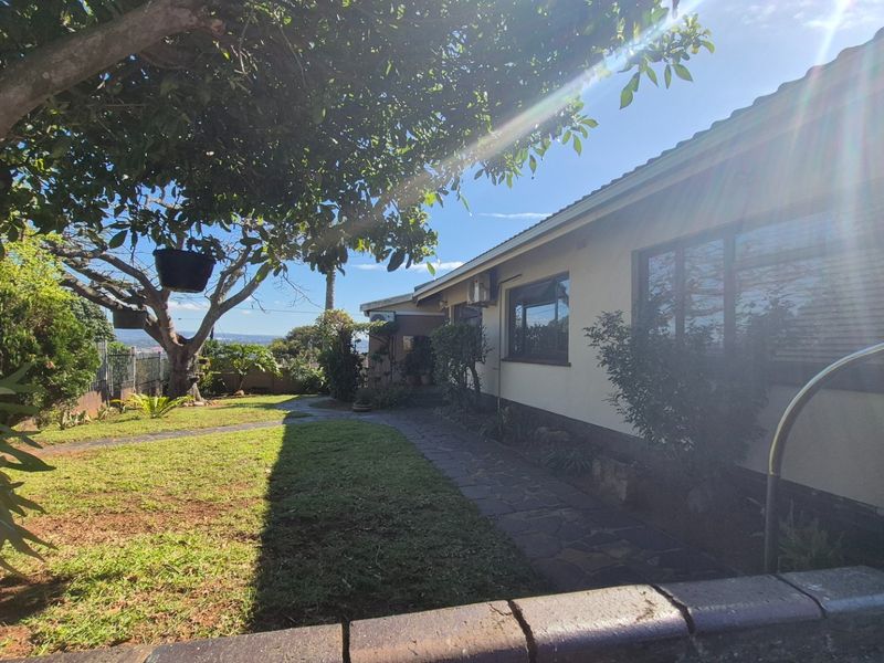 Rear view of the property featuring a paved walkway, established lawn, and exterior air conditioning unit against the building facade.