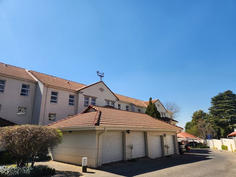 Exterior view of an apartment complex featuring a multi-bay garage block with tiled roofing and paved driveway access.